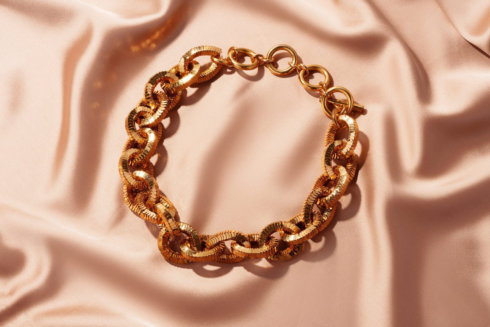 Golden chain necklace on silk background close up photo