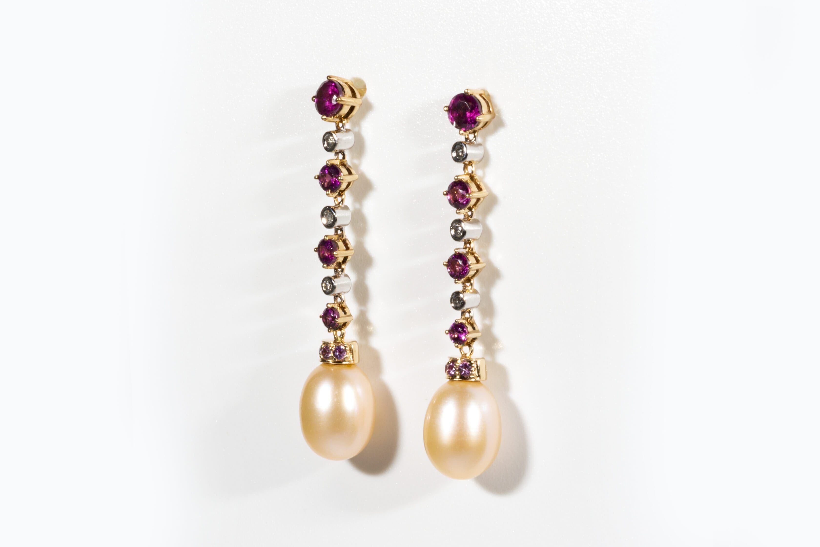 peelerie Long gold earrings with diamonds, rubies and pearls, on a white background