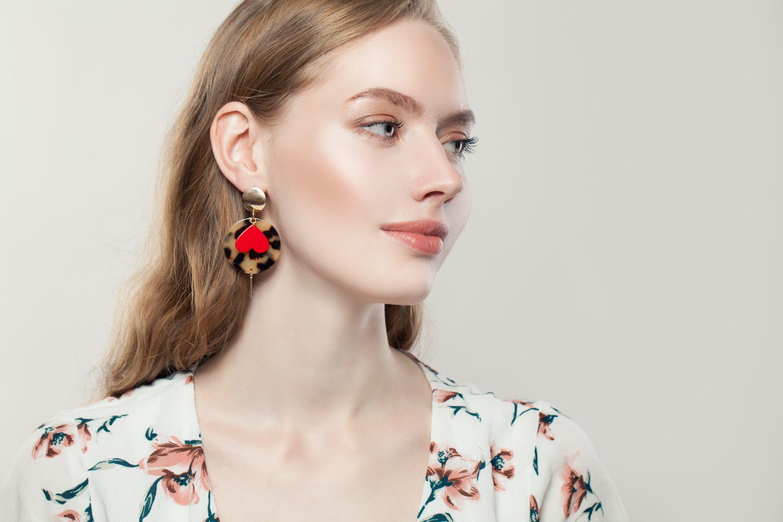 peelerie Perfect beautiful woman wearing fashion golden earrings with red heart on white background, profile