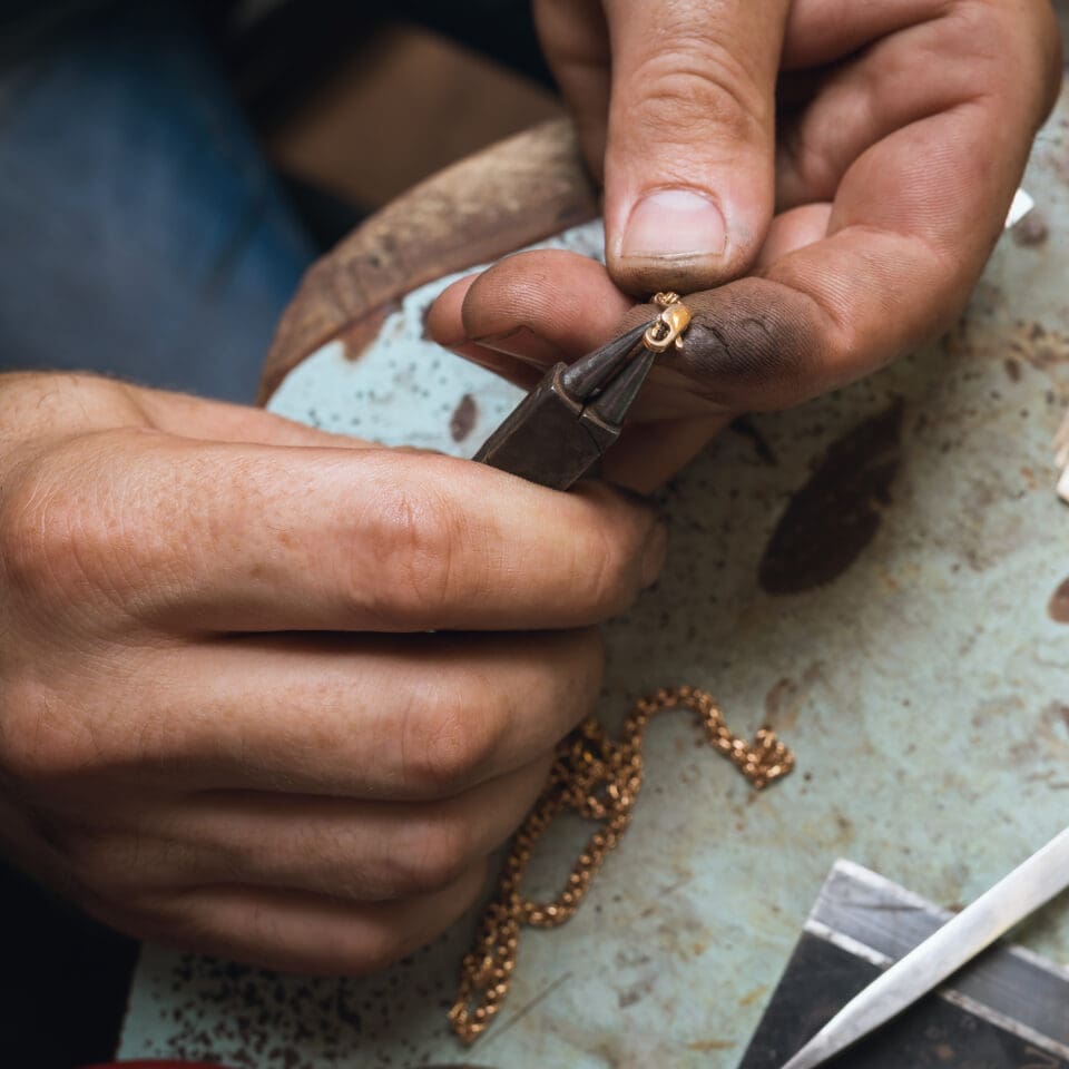 A jeweler repairs a lock on a gold chain, a close-up of a workflow